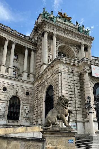 The Austrian National Library in Vienna photographed from the outside. A large lion statue is placed at the entrance.
