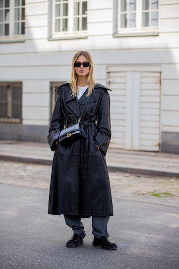 @alessawinter wearing a black leather coat, wide and long grey fabric trousers. She combined our CPH1001 vitello black clear to this outfit. With her cool black sunglasses on, she stands on the streets of Copenhagen.