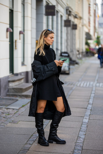 You can see @alessawinter standing on streets of Copenhagen in her all black everything look. She is wearing a black oversized raincoat from Balenciaga, a black turtleneck sweater, a black skirt and the CPH551 in vitello black. With her black sunglasses on her head, she is reading a message on her mobile phone.