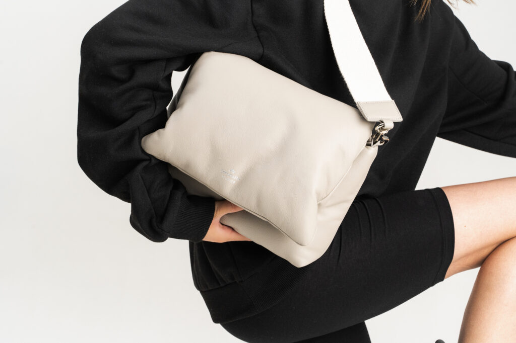 This picture partly shows a person holding the CPH Bag 11 in nappa stone. The person is wearing black loungewear. 