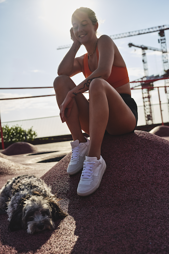 Josephine Jein is sitting at the Konditaget Lüders car park roof terrace, aka "PARK'N'PLAY". She loves to go there for boxing. She is sitting there with her dog and wearing a sporty outfit with CPH461 calf white.