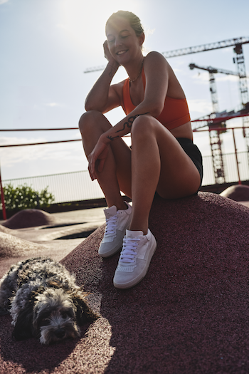 Josephine Jein is sitting at the Konditaget Lüders car park roof terrace, aka "PARK'N'PLAY". She loves to go there for boxing. She is sitting there with her dog and wearing a sporty outfit with CPH461 calf white. 