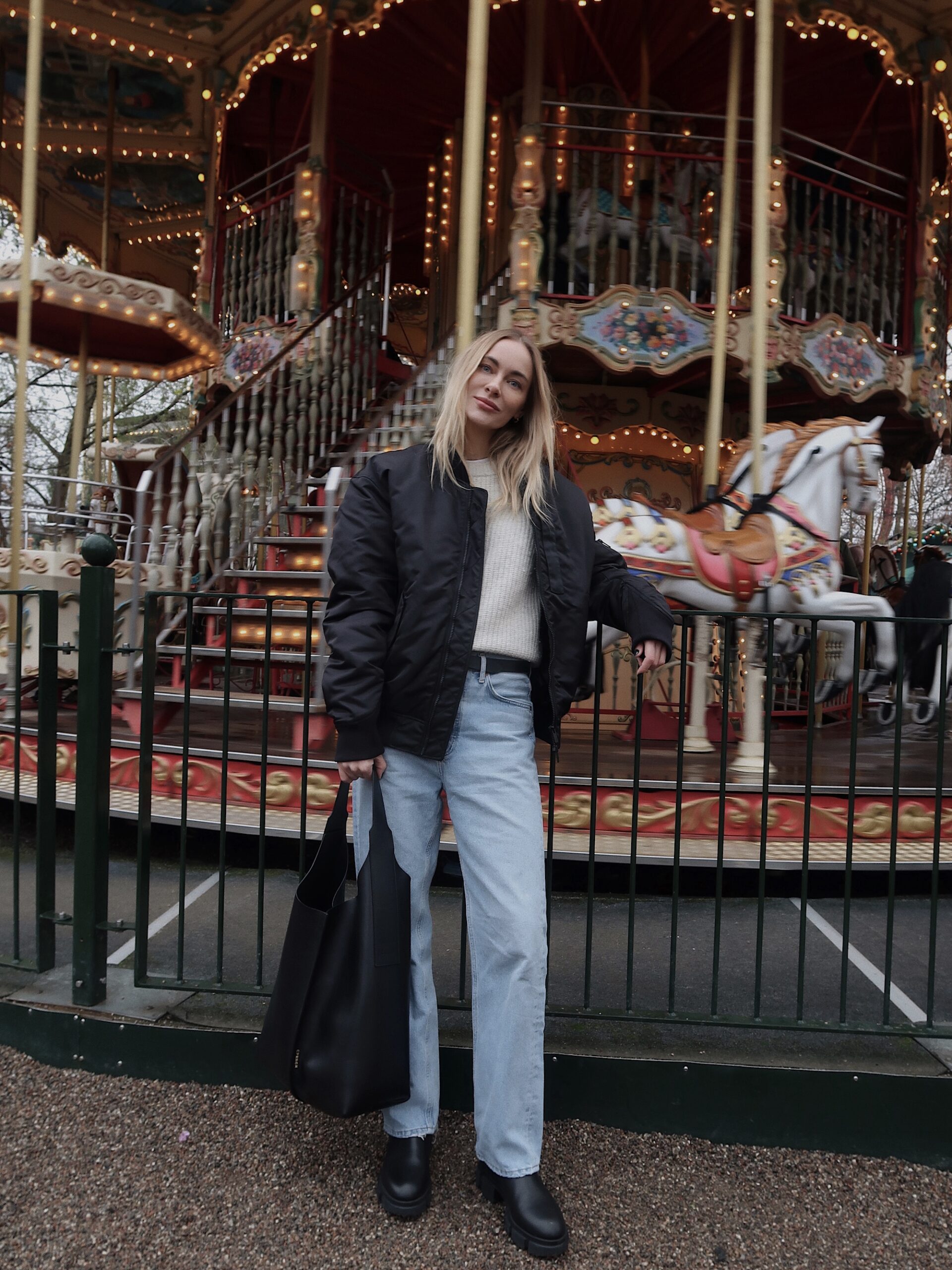 Marie Hindkaer at Tivoli in Copenhagen. She is standing in front of one carousel and wearing a casual Look combinated with CPH500 vitello black and CPH Bag 1 vitello black.