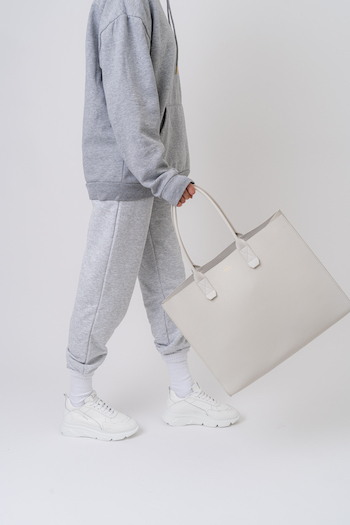 CPH Bag6 in eggshell. Model is holding a big bag in a light color in her hand. She is wearing a jogger look.