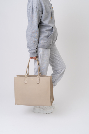 CPH Bag6 in nature. Model is holding a big bag in her hand. She is wearing a jogger look.