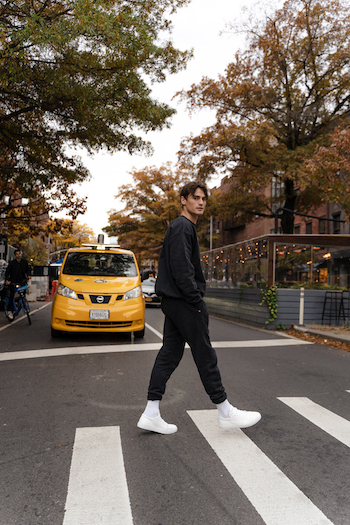 Jonas Kautenburger walk along a crosswalk in New York City. He is wearing a black loungewear set, white socks and his Copenhagen Studios sneaker CPH4M vitello white.