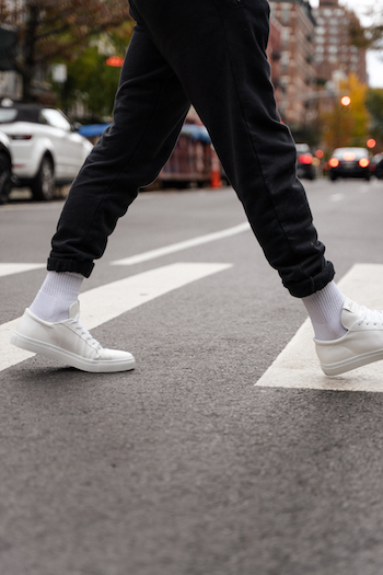 Jonas Kautenburger walk along a crosswalk in New York City. He is wearing a black loungewear set, white socks and his Copenhagen Studios sneaker CPH4M vitello white.