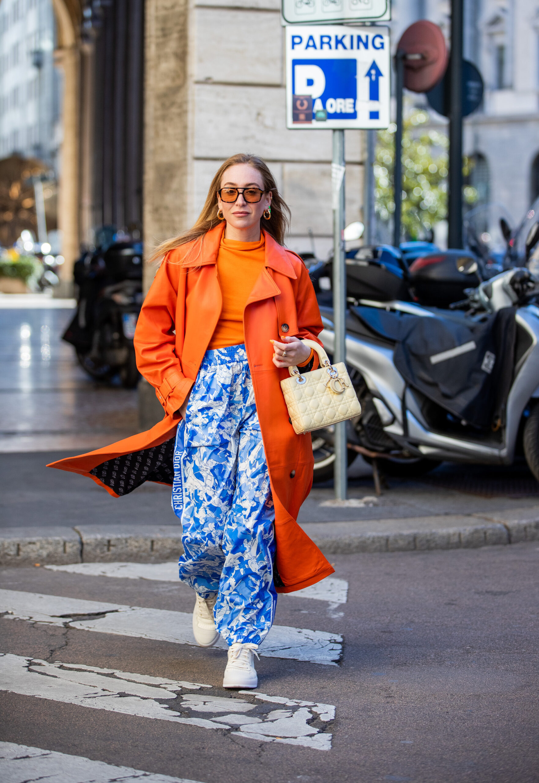 Sonia Lyson wears her CPH461 leather mix butter with an orange Trenchcoat and a blue and white flower print trousers. 