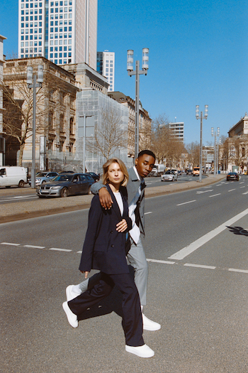 Campaign Picture from our Analogue Street Style Shooting. Two models, one female and one male, cross the street in Frankfurt. Both wearing a suit.