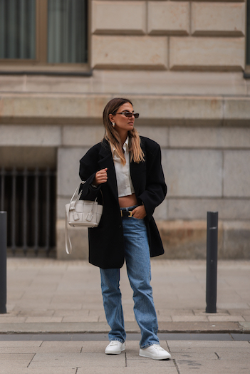 @annawntr on the streets of Hamburg city. She wears a black oversized Blazer, a cropped white blouse, denim jeans and her CPH Hamburg 2 vitello white.