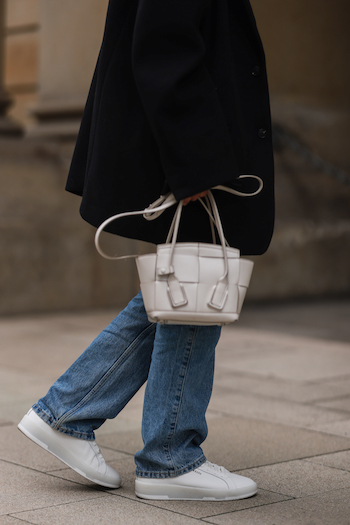 @annawntr on the streets of Hamburg city. She wears a black oversized Blazer, a cropped white blouse, denim jeans and her CPH Hamburg 2 vitello white.