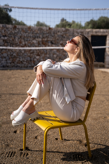 A picture from THOC Shooting. The influencer Kikidoyouloveme is sitting on a yellow chair and is wearing the chunky slides CPH231 in eggshell.