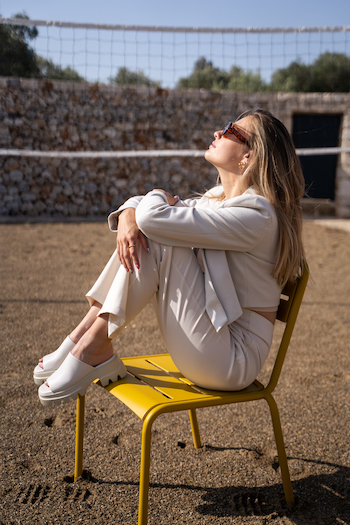 A picture from THOC Shooting. The influencer Kikidoyouloveme is sitting on a yellow chair and is wearing the chunky slides CPH231 in eggshell. 