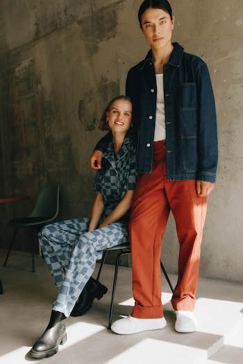 Berlin AW Shooting- Copenhagen Studios. The male Model is wearing a white new sneaker with orange pants and a denim jacket. Next to him sits a model in a denim jumpsuit with black boots.