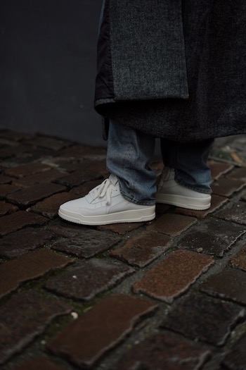 The young male influencer Erik Scholz is standing on the streets of copenhagen wearing our latest spring sneaker. The CPH161 leather mix white combined with an oversized grey wool coat and denim trousers.