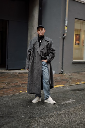 The young male influencer Erik Scholz is standing on the streets of copenhagen wearing our latest spring sneaker. The CPH161 leather mix white combined with an oversized grey wool coat and denim trousers.