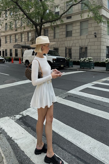 The young creative content creator @tini_leah is standing on street in the middle of manhattan, New York City. She is wearing a white mini skirt and the CPH231 sandals in vitello black.