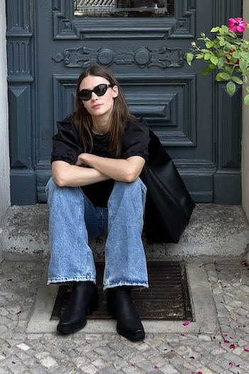 Young artist and mother Isis sitting on the floor in front of a building in Berlin. She is wearing our new iconic CPH236 nabuc black boot. Besides this she is also wearing our BOS Bag1 medium black.