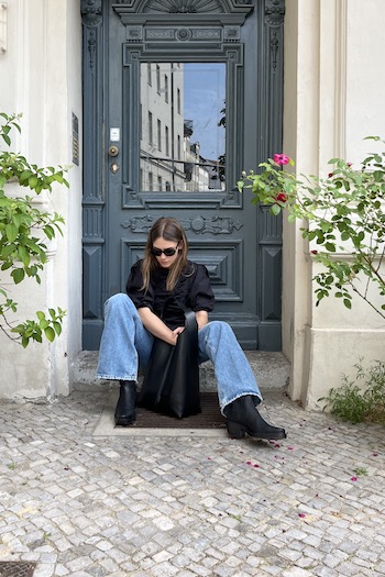 Young artist and mother Isis sitting on the floor in front of a building in Berlin. She is wearing our new iconic CPH236 nabuc black boot. Besides this she is also wearing our BOS Bag1 medium black.