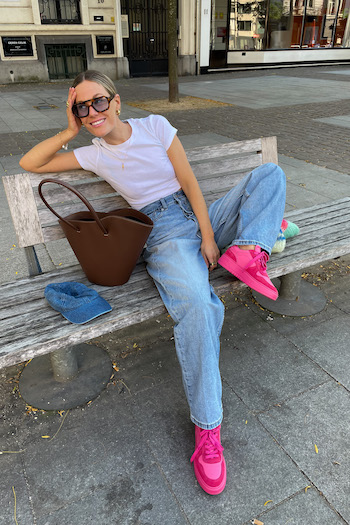 @tinvcb sitting on a bank outside and wearing the CPH X LALA BERLIN leather mix dragonfruit. She combined it with an denim jeans and a white tee.