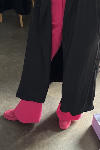 Someone wearing CPH X LALA BERLIN leather mix dragonfruit in combination with a black coat and a pink trousers.