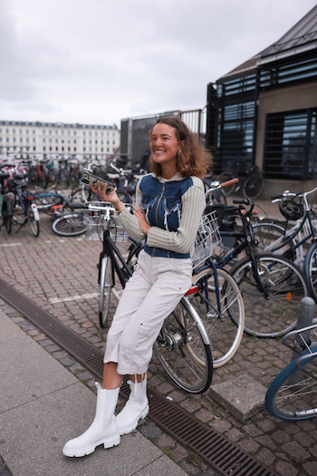 Fashion Week exclusive style, CPH500 nappa white worn by the danish Influencer Johanne Krebs. She is standing infront of several bikes in Copenhagens busy district called Nyhavn. 
