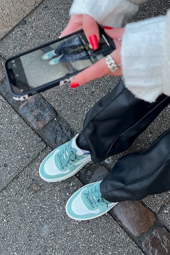 Focus on our CPH77 leather mix white/sage. The Creator Amanda Sand is taking a picture of the sneaker with her phone for her socials to give her audience some styling inspiration.