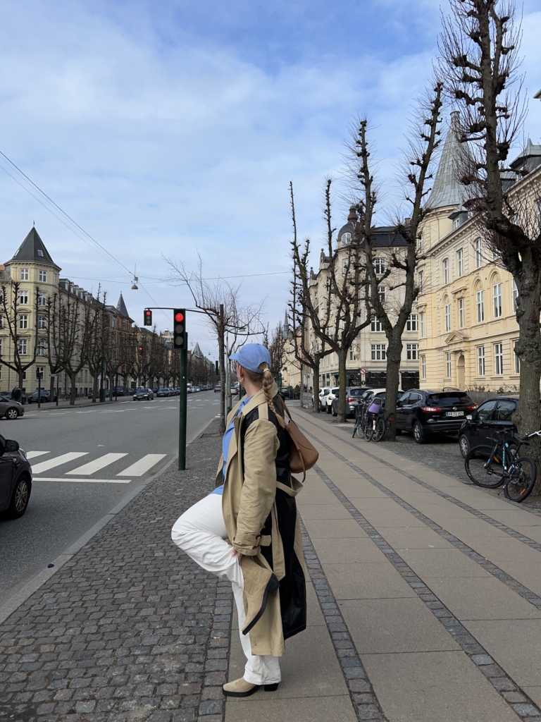 Maria Jonsson posing on the sidewalk in her CPH233 suede sand boots. She combined our boots to white pants, a trenchcoat, a blue shirt & hat. 