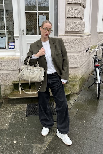 The female Creator Marleen from Münster, Germany wearing our CPH213 standing in front of a beige building.