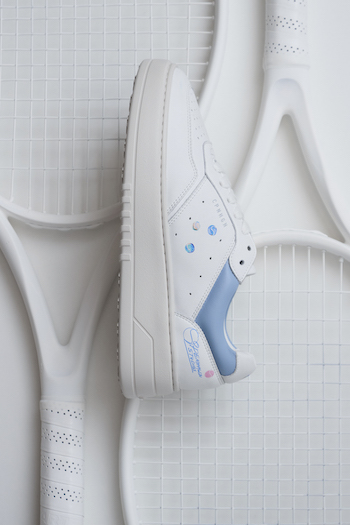 The CPH MELBOURNE leather white/light blue is in focus & laying on a racket.