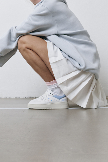 You can see a model posing in the CPH MELBOURNE wearing a tennis skirt & gray sweater.