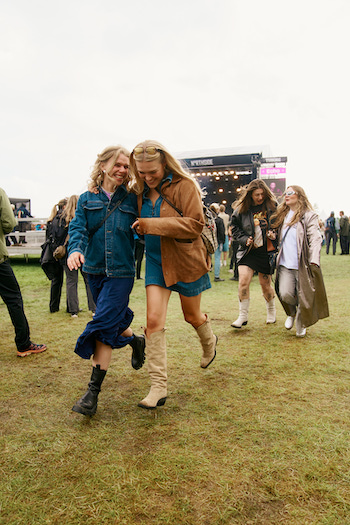 Maria and her friends enjoying the festival, dancing in front of a stage and having a great time, wearing our festival capsule.