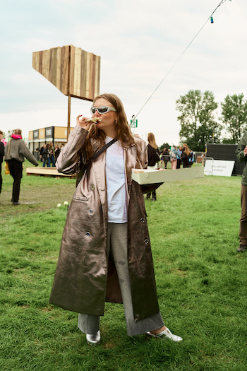 A friend of Maria at the festival eating a pizza and wearing our our CPH792 nappa silver mules to a white t-shirt, beige pants and silver trench coat.