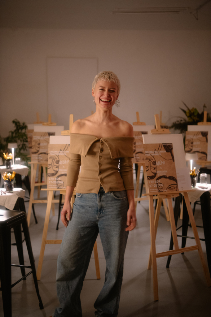 This image shows Hannah Mühi in front of the canvases at her event.